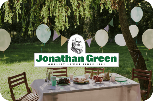 Outdoor celebration setup with a festive table, balloons, and a "Jonathan Green eGift Card" banner.