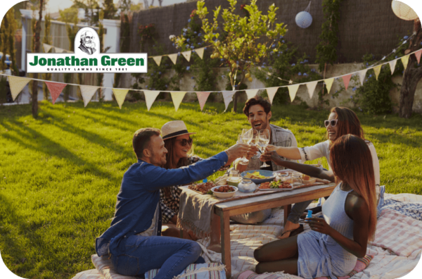 Friends enjoying an outdoor gathering with a Jonathan Green eGift Card toast at a sunlit picnic.
