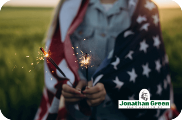 Person holding sparklers wrapped in the American flag stands in a field at dusk, evoking the spirit of a Jonathan Green eGift Card.