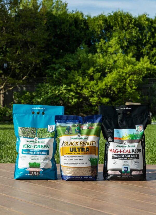 Three different Grass Seed & Fertilizer Bundle for Acidic Soil on a grassy surface outdoors.