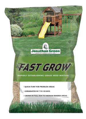 A bag of Fast Grow Grass Seed mixture with information highlights, placed against a backdrop of a lush lawn with a wooden playset.