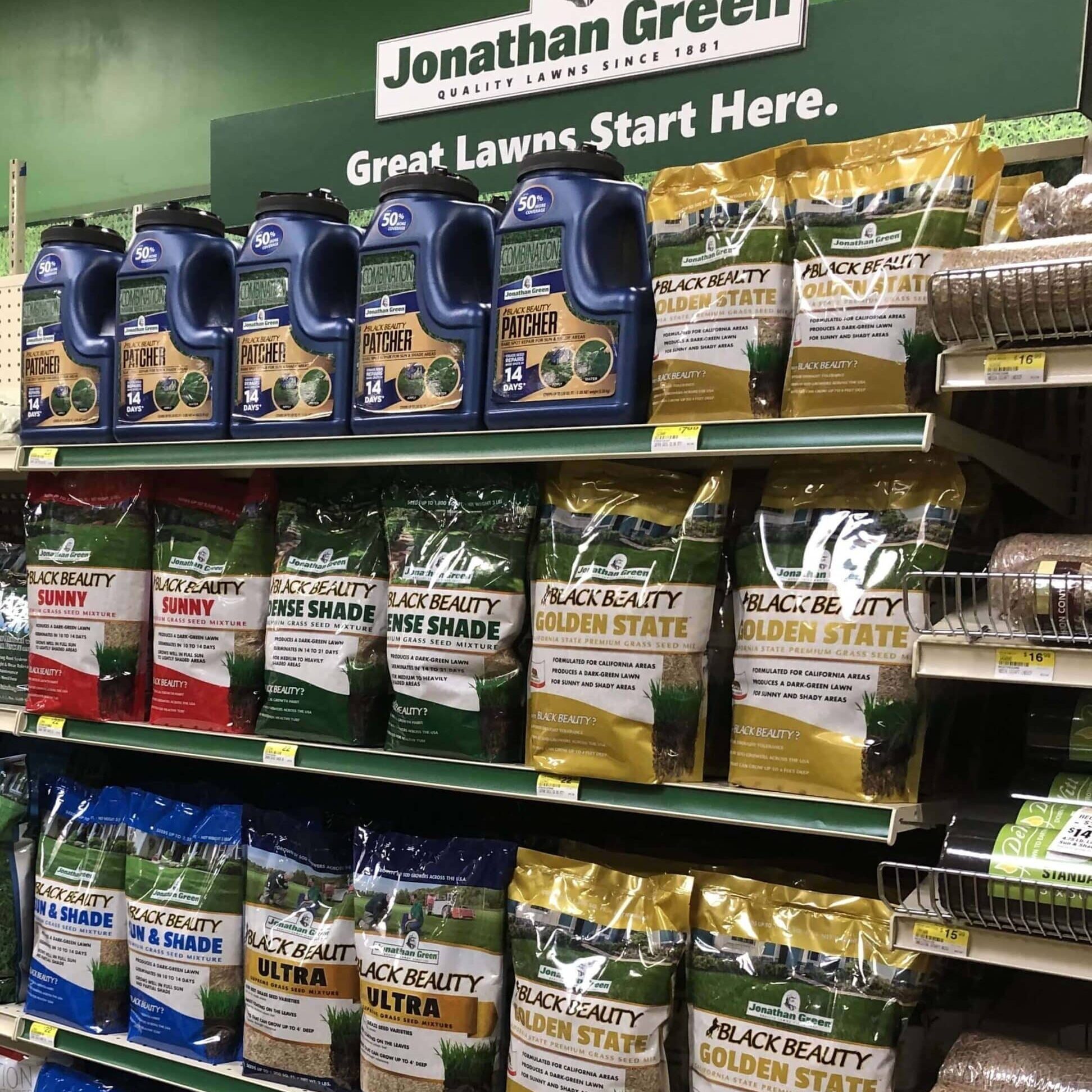 Aisle in a store displaying various Jonathan Green grass seed products under a sign stating "Great Lawns Start Here," available at Jonathan Green grass seed retailers.